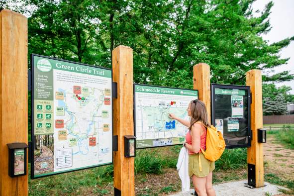 Woman looking over signs for the Green Circle Trail in Stevens Point, WI.