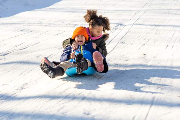 Kids sledding down a hill at Iverson Park