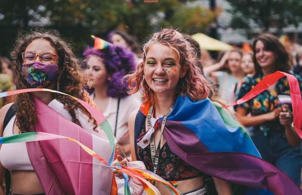 women celebrating pride parade with rainbow flags and smiling faces
