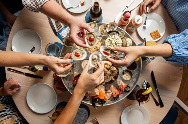 Friends share raw oysters, crab, and other chilled seafood as part of the seafood Plateau at Delacroix