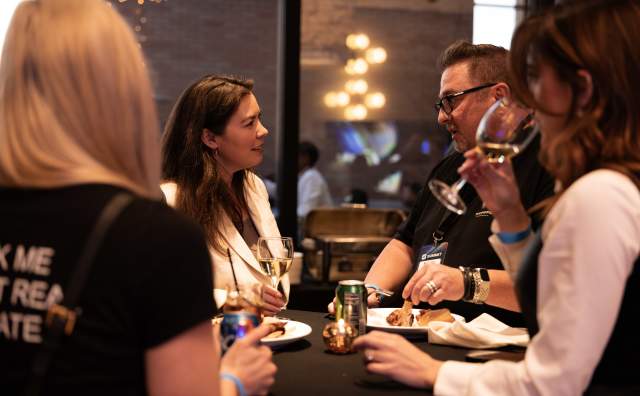 People standing at table talking with drinks and appetizers