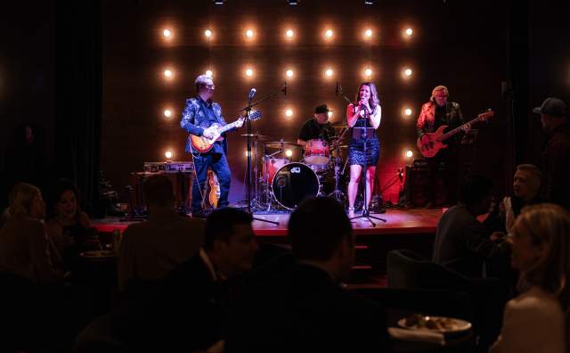 Band playing on stage backlit by a grid of lights