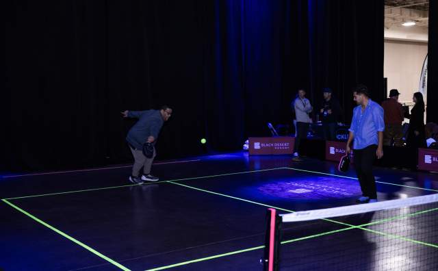 Glow in the dark pickleball court with 2 players on it