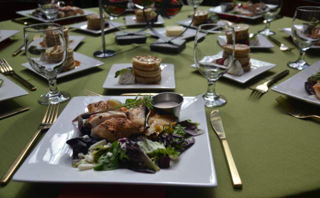 Chicken salad on square plates set on a green table cloth with utensils and dessert