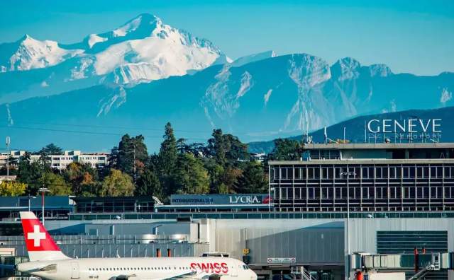 Geneva Airport with Swiss Air plane in the foreground and airport terminal with snow covered swiss alps in the background