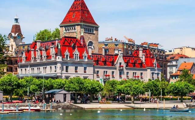 Swiss style building with distinctive red roof on a river