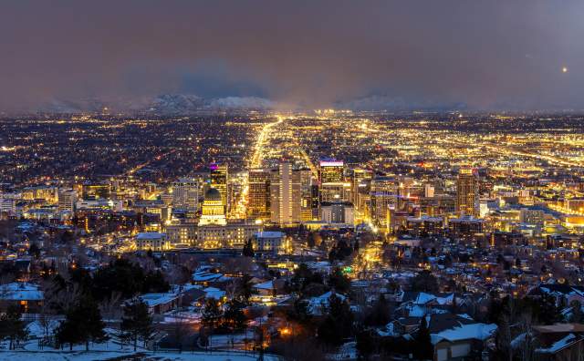 Aerial view of Salt Lake at night looking south down main street from above the capitol building. The city is lit up with yellow lights.