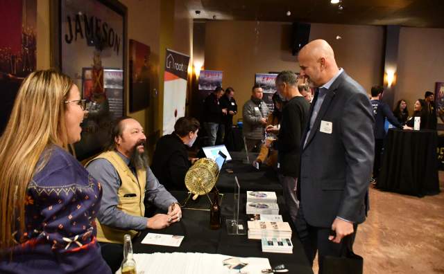 3 people standing at a table with brochures on it