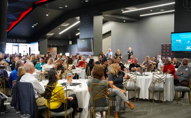 Crowd of people sitting at tables listening to a speaker that is just out of view