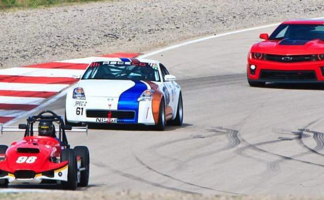 Red go cart, white car with blue and orange racing stripes, and red race car on a concrete track