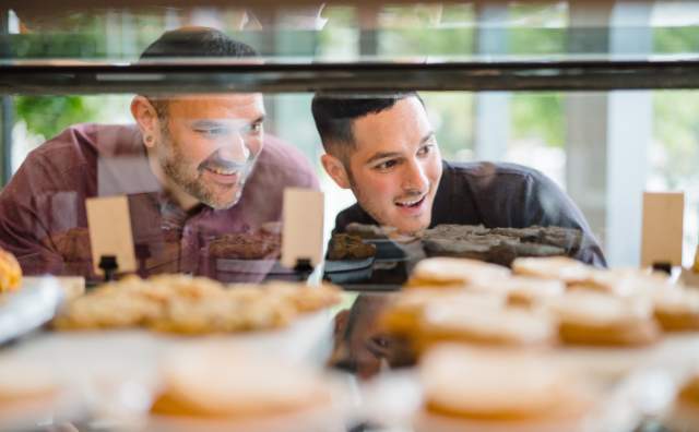 Couple Looking Through Glass at Bakery