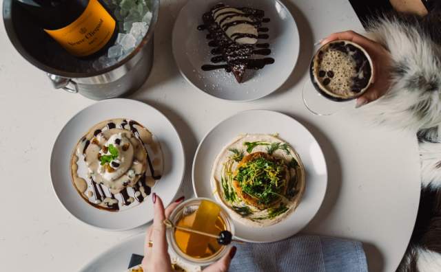 Image of people "cheersing" at a table with different food an drinks.