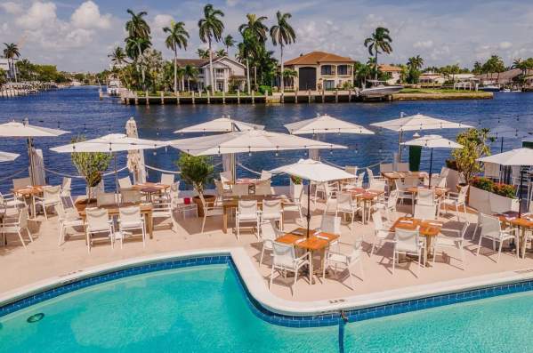 the view from the back of Sands Harbor Resort & Marina that shows part of the pool, several tables with umbrellas and the Intracoastal Waterway in the background