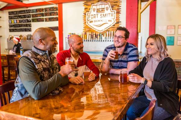 A group of 4 friends enjoy beverages together at Fort Smith Brewing Company.