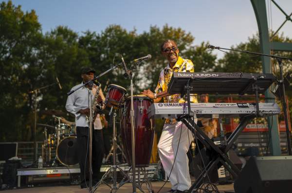 A man plays the saxophone while another man plays the drums on stage at Fort Smith's 4th of July event.