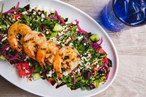 Four grilled shrimp atop a bed of greens with pickled beat shavings and chunks of Watermelon