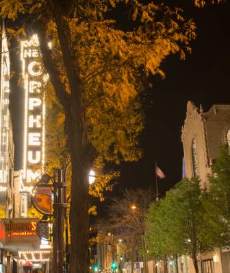 A wide shot of State Street at night in Fall, with a lit up Oprhuem sign in the foreground