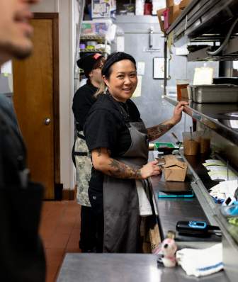 A southeast Asian woman. chef Jamie Brown-Soukaseume, stands in the kitchen at Ahan and looks to the camera.