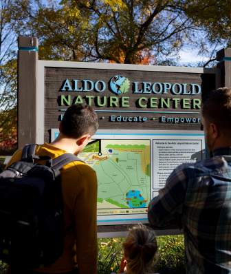 Two dads and their daughters reading a sign at the Aldo Leopold Nature Center