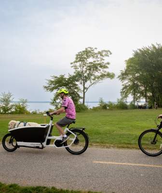 A man riding a bike with an attachment at the front for his dog and a woman riding her bike behind him on the LakeMonona Loop.