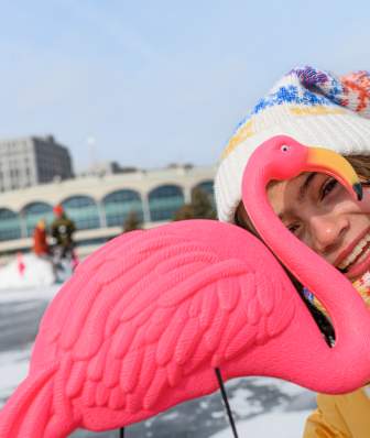 A young girl peaks through a plastic pink flamingo while standing on a frozen Lake Monona.