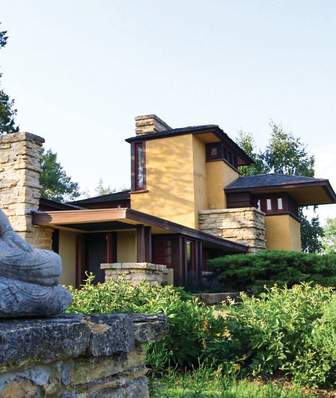 A statute sits outside of a Frank Lloyd Wright-designed building