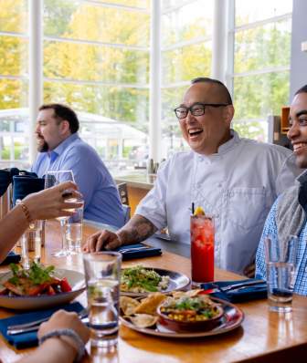 Chef Tory Miller talks to a table of people while they eat their meal at Graze