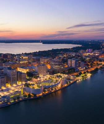 An aerial view of Downtown Madison and the isthmus lit up as dusk approaches