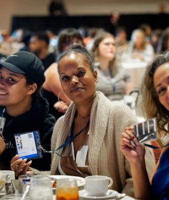 Three Black women sitting at a banquet table at a mental health conference in Madison