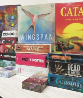 A stack of board games inside of Noble Knight Games