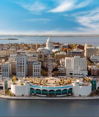 An aerial view of the Madison skyline featuring Lake Monona, Monona Terrace, The Capitol building and Lake Mendota in the background