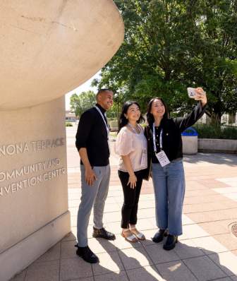 Three conference attendees taking a selfie outside of Monona Terrace Community & Convention Center