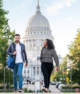 Two people walking in Madison WI with State Capitol Building in background