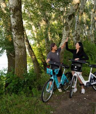 Two cyclists high five each other in front of Lake Monona and Olin Park