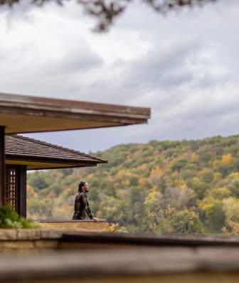 A woman looks out onto the rolling hills of Spring Green from the balcony at Taliesin