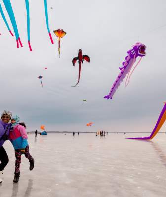 A black woman and her daughter taking a selfie in front of the kite show at the Frozen Assets Festival on Lake Mendota.