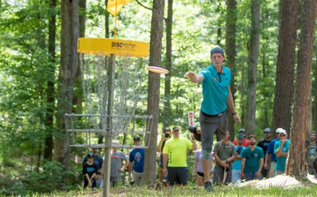Pro disc golfer throwing disc into basket at PDGA International Disc Golf Center