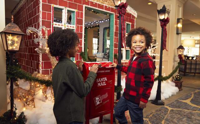 Children dropping letters to Santa Clause in holiday mailbox