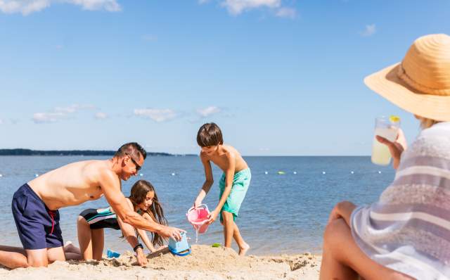Family playing in sand while mom watches on Yorktown Beach