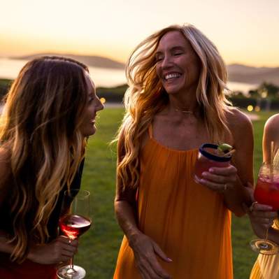 Three women talking and smiling with curled hair at sunset