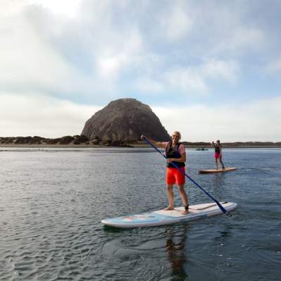 Paddleboarders on calm water with Morro Rock in background