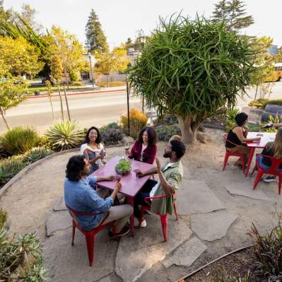 Group of people sitting outside at red tables wine tasting in downtown