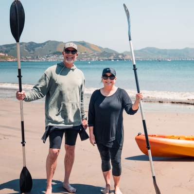 Couple holding kayak oars standing on the beach in Avila Beach