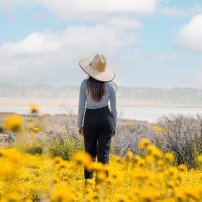 Girl in a hat looking at Soda Lake on the Carrizo Plains with wildflowers in the foreground