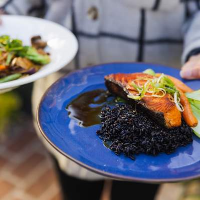 Server holding two bright plates of food
