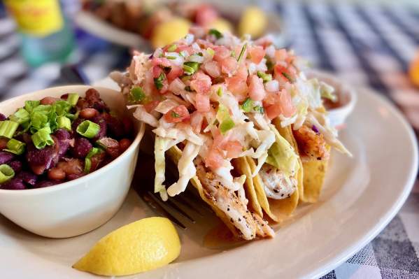 A plate of fish tacos with a side of black beans.