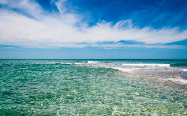 Photo of ocean, beautiful clear water with slight waves breaking on shoal in front of Gasparilla Island at Gasparilla Pass in Charlotte County.