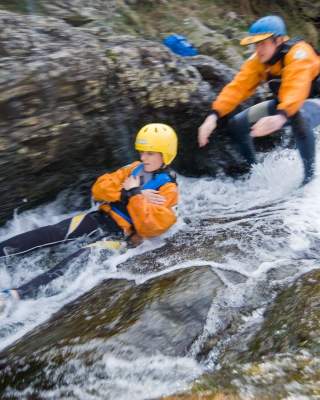Bouldering at Bloody Bridge in Newcastle, County Down. Man slides down whitewater rocks.