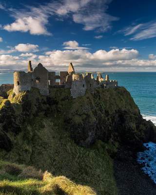 Medieval Dunluce Castle with blue skies.