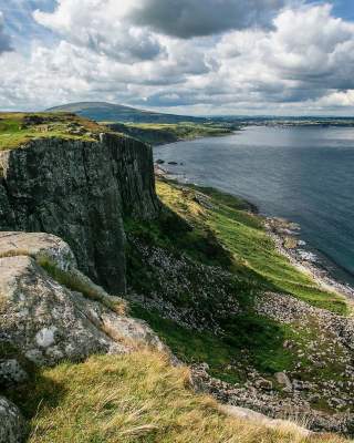 Cliff view from Fair head over looking blue still water and blue skies